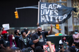 Activists speak under a large BLM flag at a Black Lives Matter rally