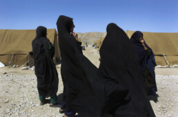 Afghan women stand outside tents housing refugees