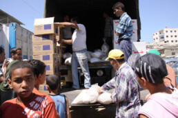 Workers offload aid boxes from a truck to Gaza residents