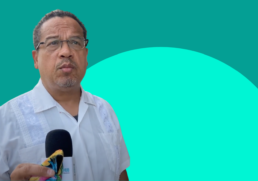 Keith Ellison speaks into a microphone on a two-tone green background