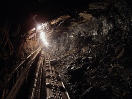 Tracks in a coal mine lead to a sliver of light