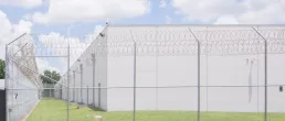 A detention center surrounded by barbed wire shot in the middle of the day