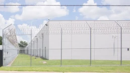 A detention center surrounded by barbed wire shot in the middle of the day
