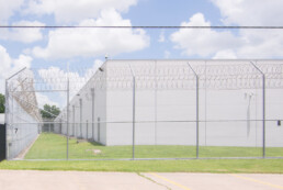 A detention center surrounded by barbed wire shot in the middle of the day