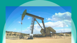 An oil well in the desert against a blue sky and a green background