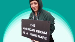 woman holding sign that says the american dream is a nightmare