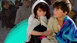 Two Afghan Children sit in front of a larger group
