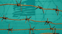 barbed wire and fences in front of tattered american flag at Guantanamo bay Cuba