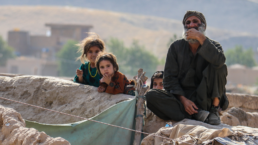 An Afghan man sits with some children