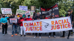 climate justice is racial justice banner held by climate activists