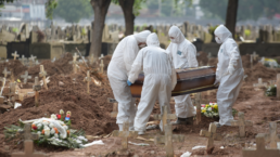 People in hazmat suits bury a covid victim in a muddy cemetery