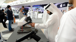 An Arab man in traditional clothes checks a new model of a gun visiting weapons exhibition IDEX in Abu Dhabi, UAE