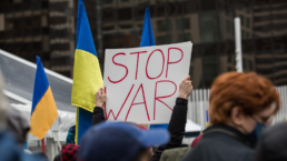 he sign STOP War in the crowd with Ukrainian flags at the antiwar protest in the centre of downtown