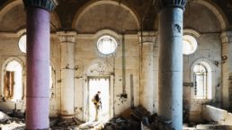 A military contractor stands in the doorway of a ruined mosque