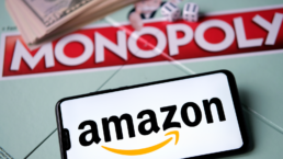 amazon app on phone on top of monopoly board covered in money