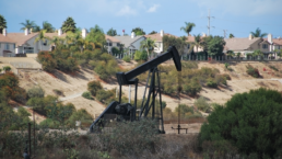 A pumpjack derrick drilling for oil in Los Angeles, next to a residential area