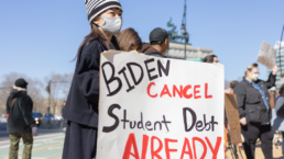 Protestors hold a sign at an outdoor protest against student debt