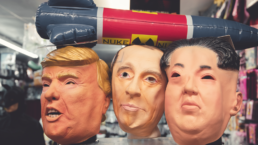 Masks of Trump, Putin and Kim Jong Un under a balloon of a nuclear missile
