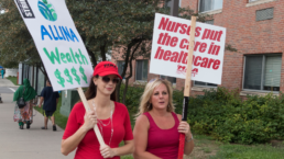 Nurses on the picket line carrying placards protesting their new Allina Health benefits package.