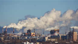Emissions bellow from smokestacks with an urban environment in the foreground