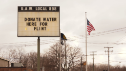 small town sign reads donate water here for flint