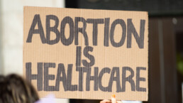 A hand holding a sign supporting abortion as healthcare during a rally for abortion justice.