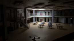 Light from skylight into common area of abandoned state prison cell block.