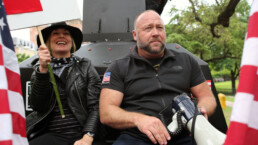 Alex Jones, with his wife Erika Wulff Jones, sits in the bed of an armored truck before leaving a rally protesting Covid-19 stay at home orders promoted by Infowars.
