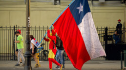 Man dressed in red and yellow carries the Chilean flag down the street