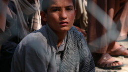 An Afghan boy sits in a refugee camp