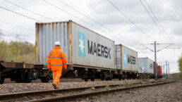 A rail worker walks behind a train car hauling freight