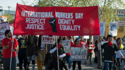 Workers carry a large banner on international wokrers day