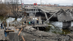 People cross a destroyed bridge as they evacuate the city of Irpin, northwest of Kyiv, during heavy shelling and bombing