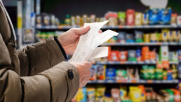man viewing receipts in supermarket and tracking prices