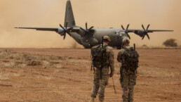 A US military plane lands in Africa while personnel watches