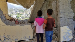 Children in Yemen stand in a bombed out building