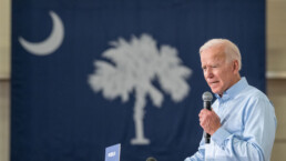 Joe Biden speaks with the South Carolina flag behind him