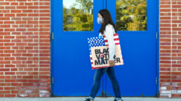 woman holds a black votes matter sign while walking away from a polling place or protest