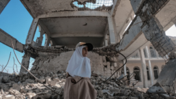 Yemeni girl sitting on rubble of school