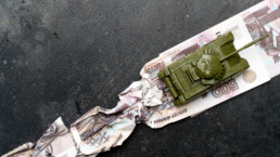 Economic crisis in Russia concept. Toy military tank on Russian rubles. War conflict in Ukraine, economic sanctions and inflation in Russia