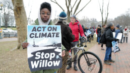 A activist at the White House holds a poster calling for the cessation of the Willow pipeline in Alaska in taking action on climate change.