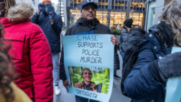 protestor with sign that says Chase supports police murder Tortuguita