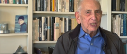 Dan Ellsberg sits with a bookshelf behind him