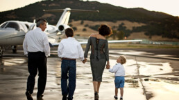 Family walking towards a private jet holding hands