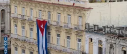 Large Cuban flag hanging vertically on a facade of colonial building Inglaterra Hotel in the historical center of Old Havana.