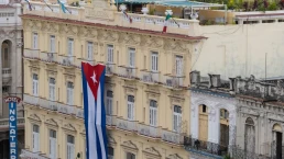 Large Cuban flag hanging vertically on a facade of colonial building Inglaterra Hotel in the historical center of Old Havana.
