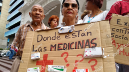 protestors hold signs protesting the lack of medicine in Venezuela