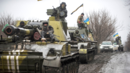 tanks in a line with Ukrainian flags mounted on them