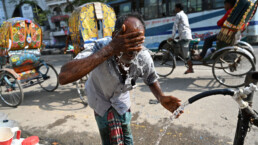 A Man washing his face with water at a roadside water pipeline during high temperature weather day in Dhaka, Bangladesh