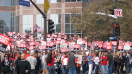 striking sag workers stand outside a building at an intersection